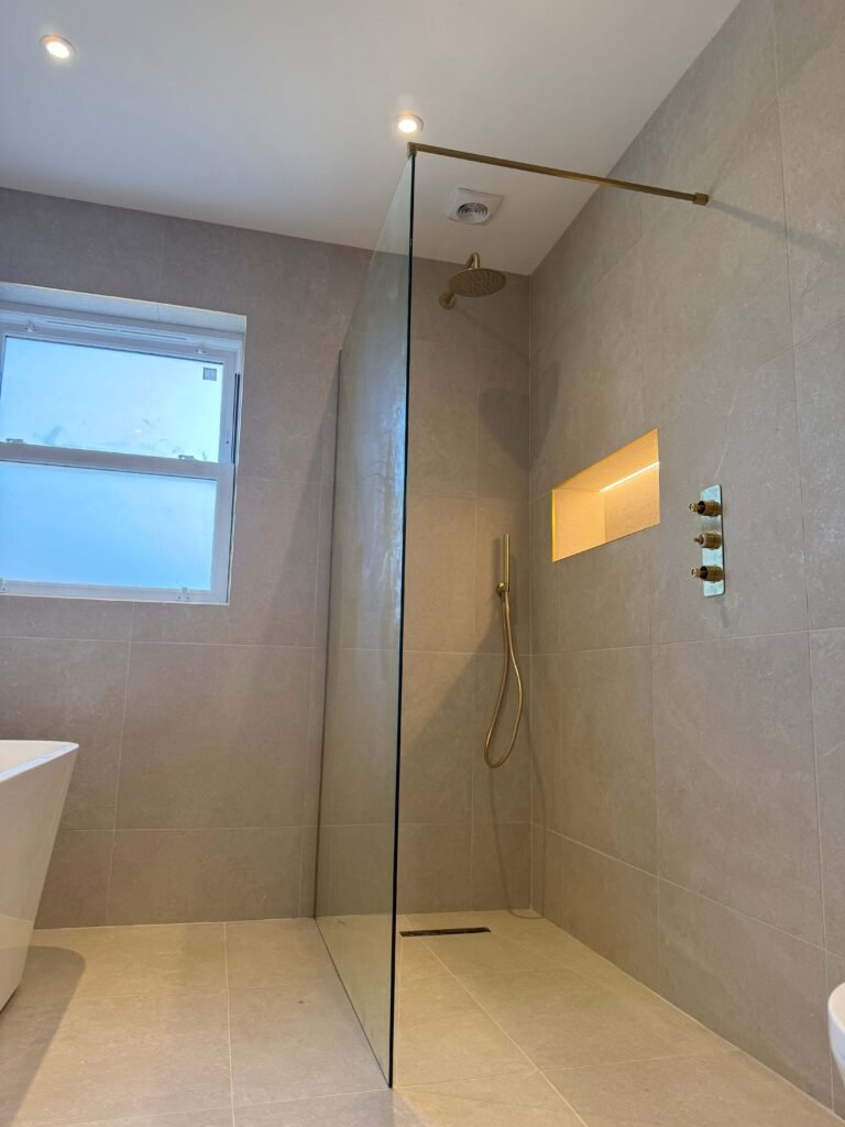 Frameless glass divider giving a sleek touch to Hove shower room.